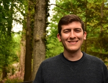 Man in forest smiles and looks forward.